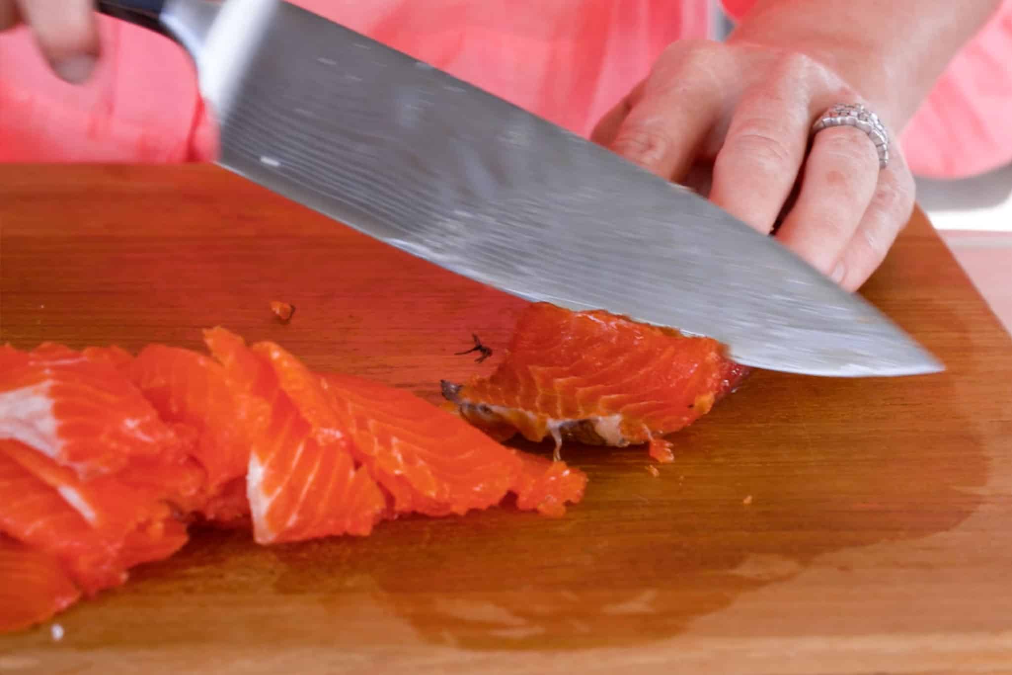 Thinly slicing the salmon, being careful to keep the skin on.